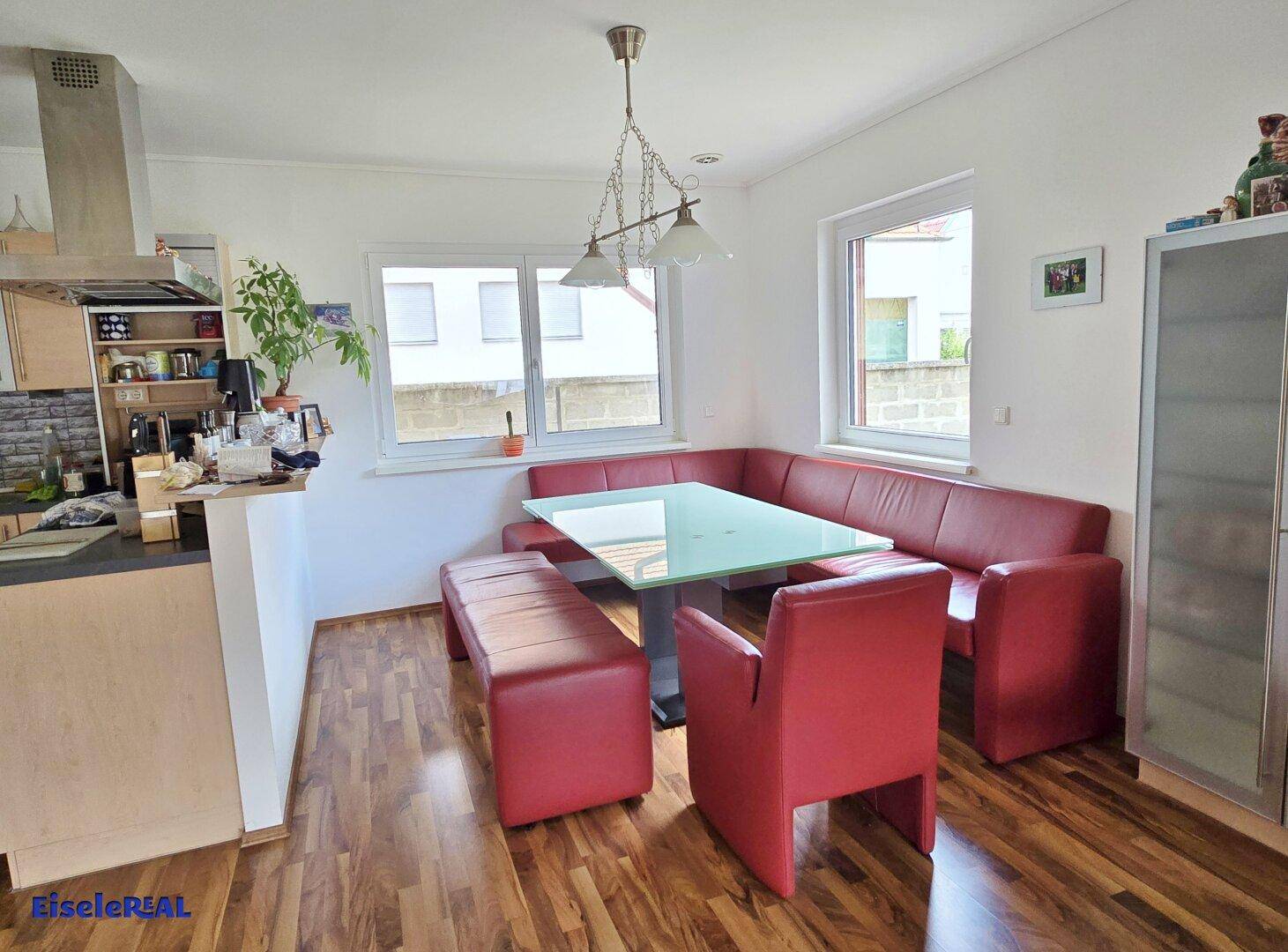 Gemütlicher Essbereich mit roter Eckbank und Holzboden neben der Küche.