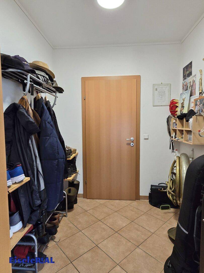 Eingangsbereich mit Garderobe, Fliesenboden und Holztür.