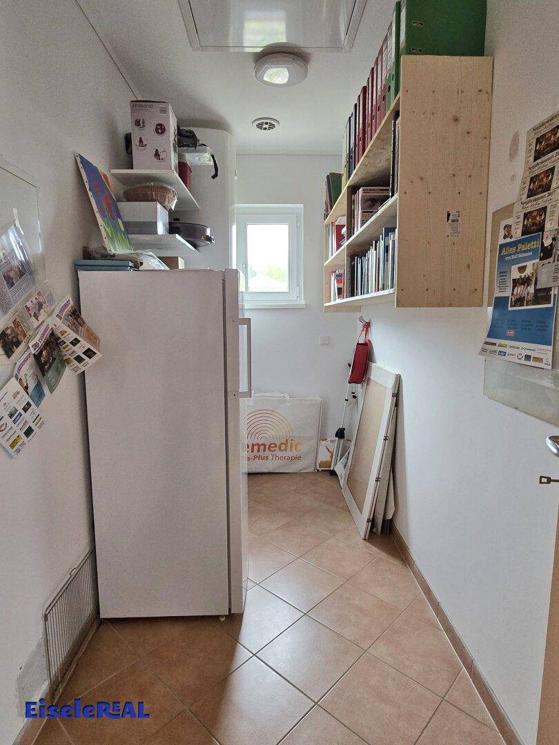 Praktischer Abstellraum mit Regalen, Kühlschrank und Fenster.