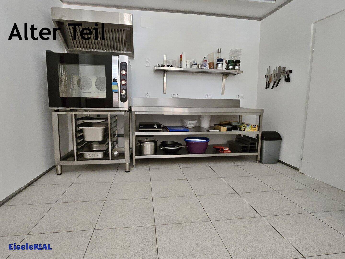 Gewerbliche Küche mit großem Ofen, Dunstabzugshaube und Edelstahl-Arbeitsflächen, sehr funktional.