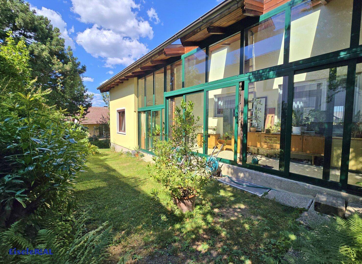 Verglaster Wintergarten mit Blick in den Garten und viel Tageslicht.