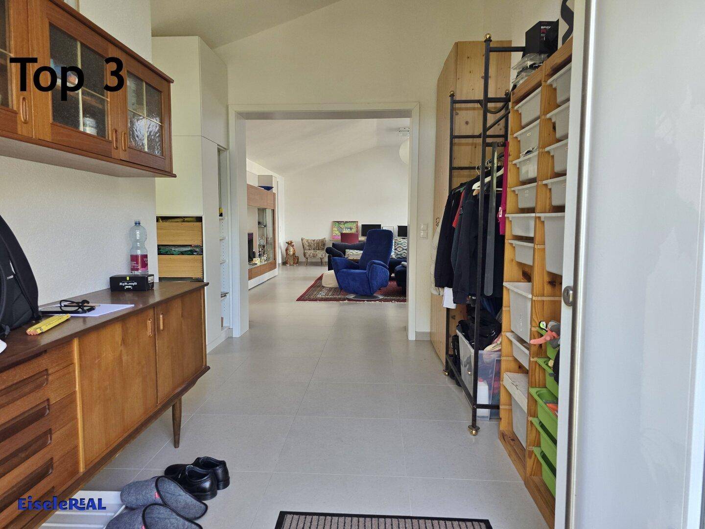 Heller Eingangsbereich mit Fliesenboden, Garderobe und Durchgang zum Wohnbereich.