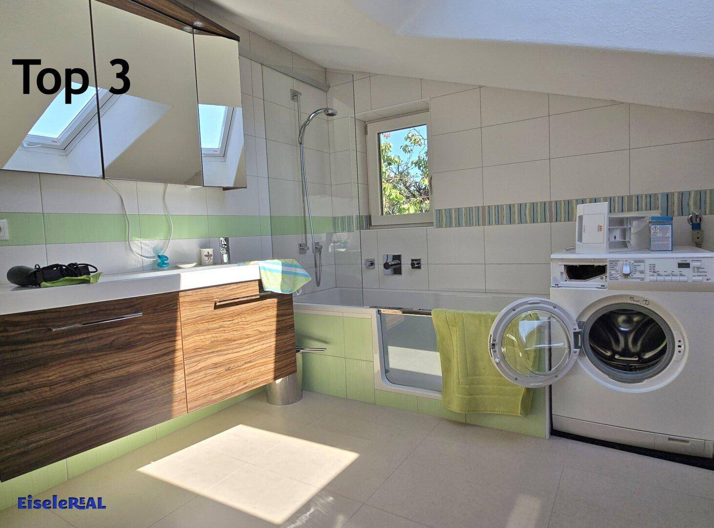 Geräumiges Badezimmer mit Badewanne, Waschmaschine und Dachfenster für viel Licht.
