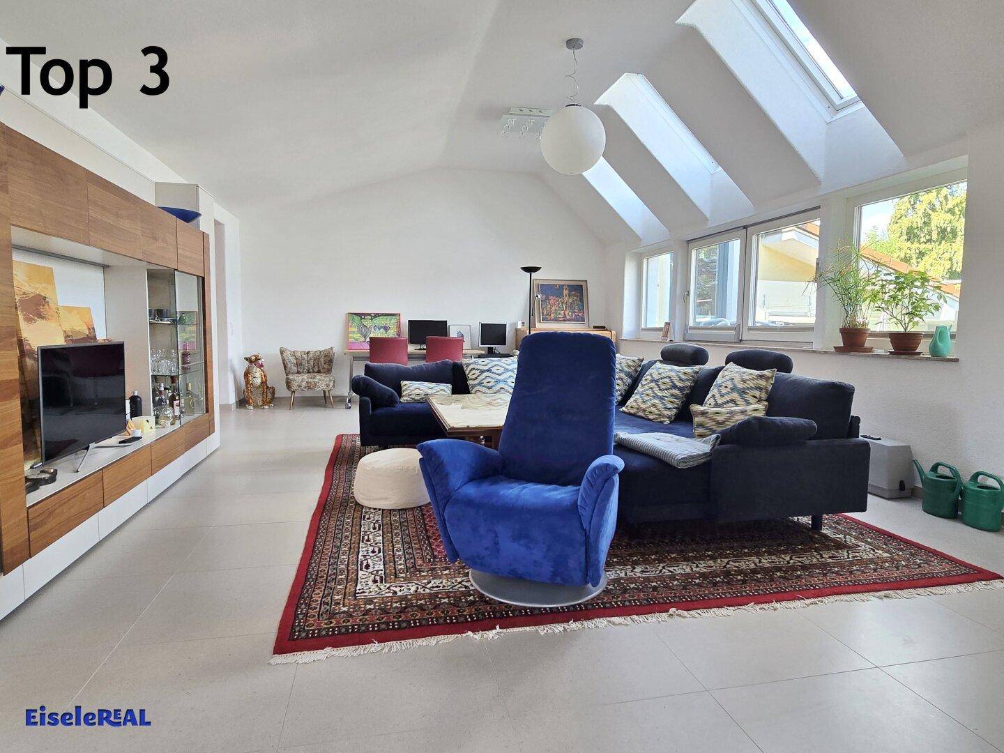 Helles Wohnzimmer mit hohen Decken, Dachfenstern und großen Fenstern mit Ausblick.