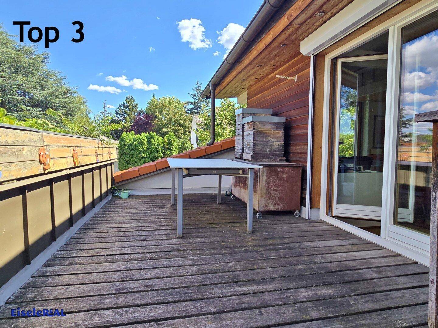 Geräumige Holzterrasse mit Tisch und Blick ins Grüne, ideal zum Entspannen.