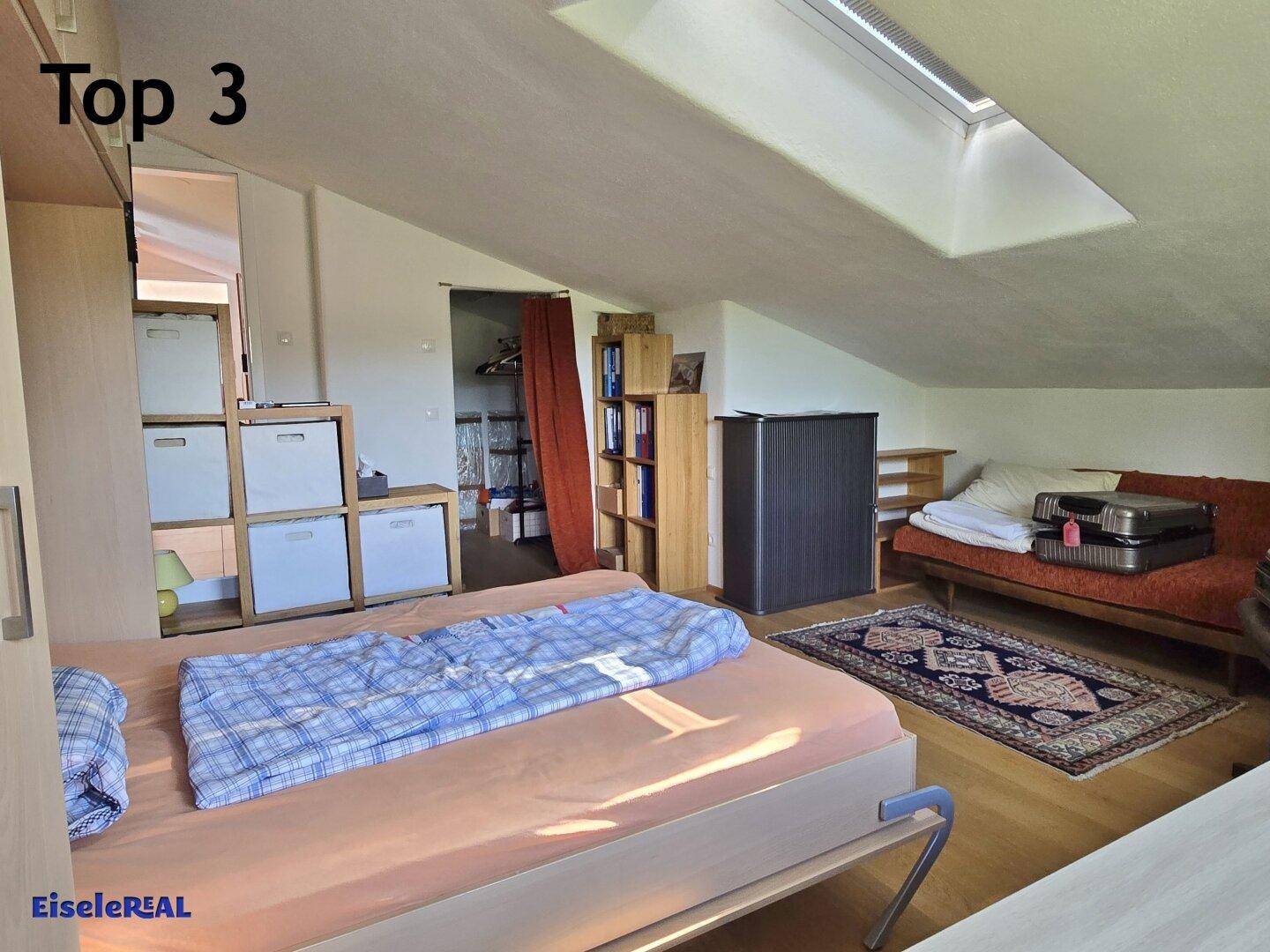 Gemütliches Schlafzimmer im Dachgeschoss mit Schräge, Dachfenster und Holzboden.
