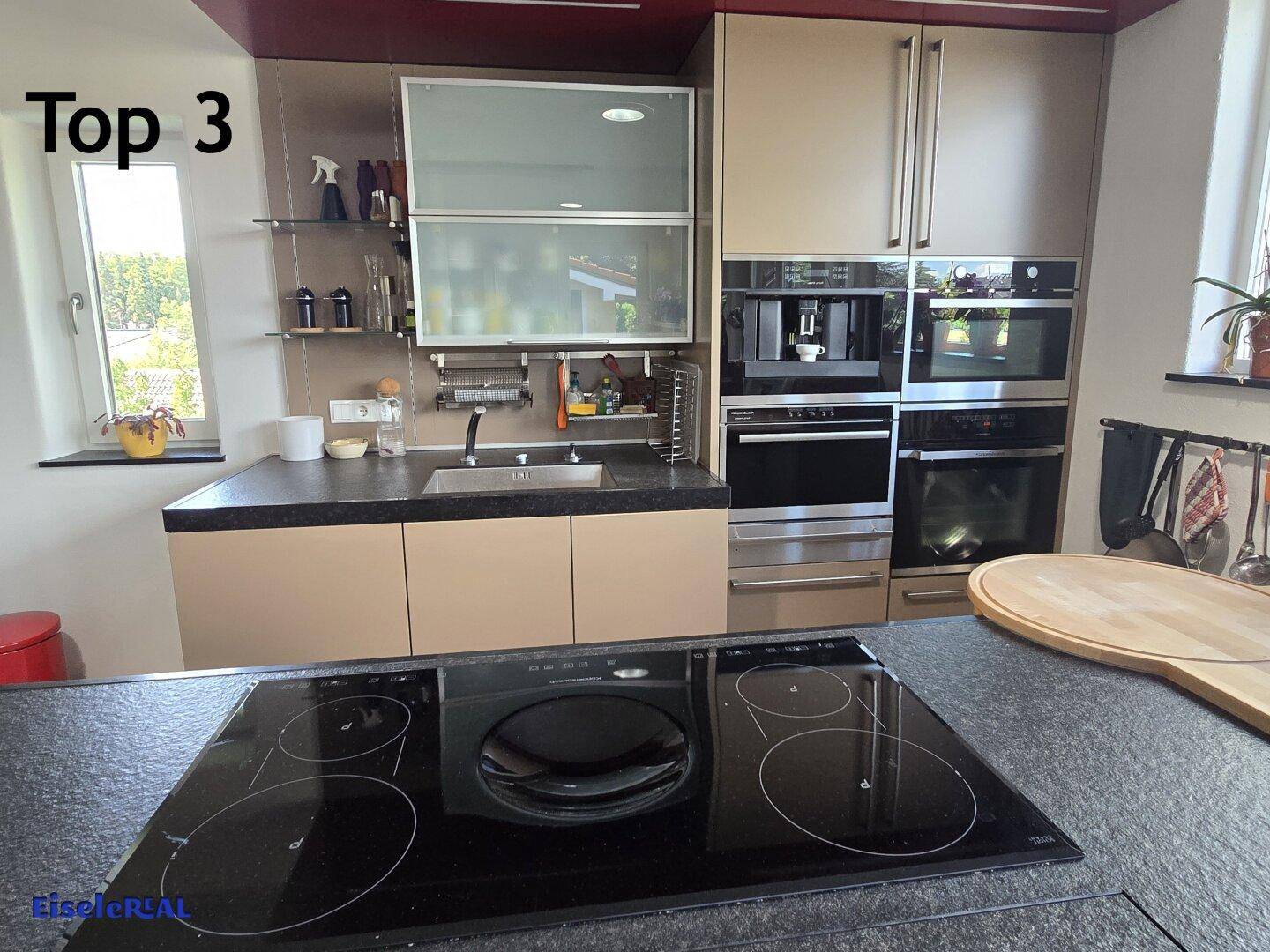 Detailansicht der modernen Küche mit integriertem Backofen, Kaffeemaschine und Induktionskochfeld auf der Insel.