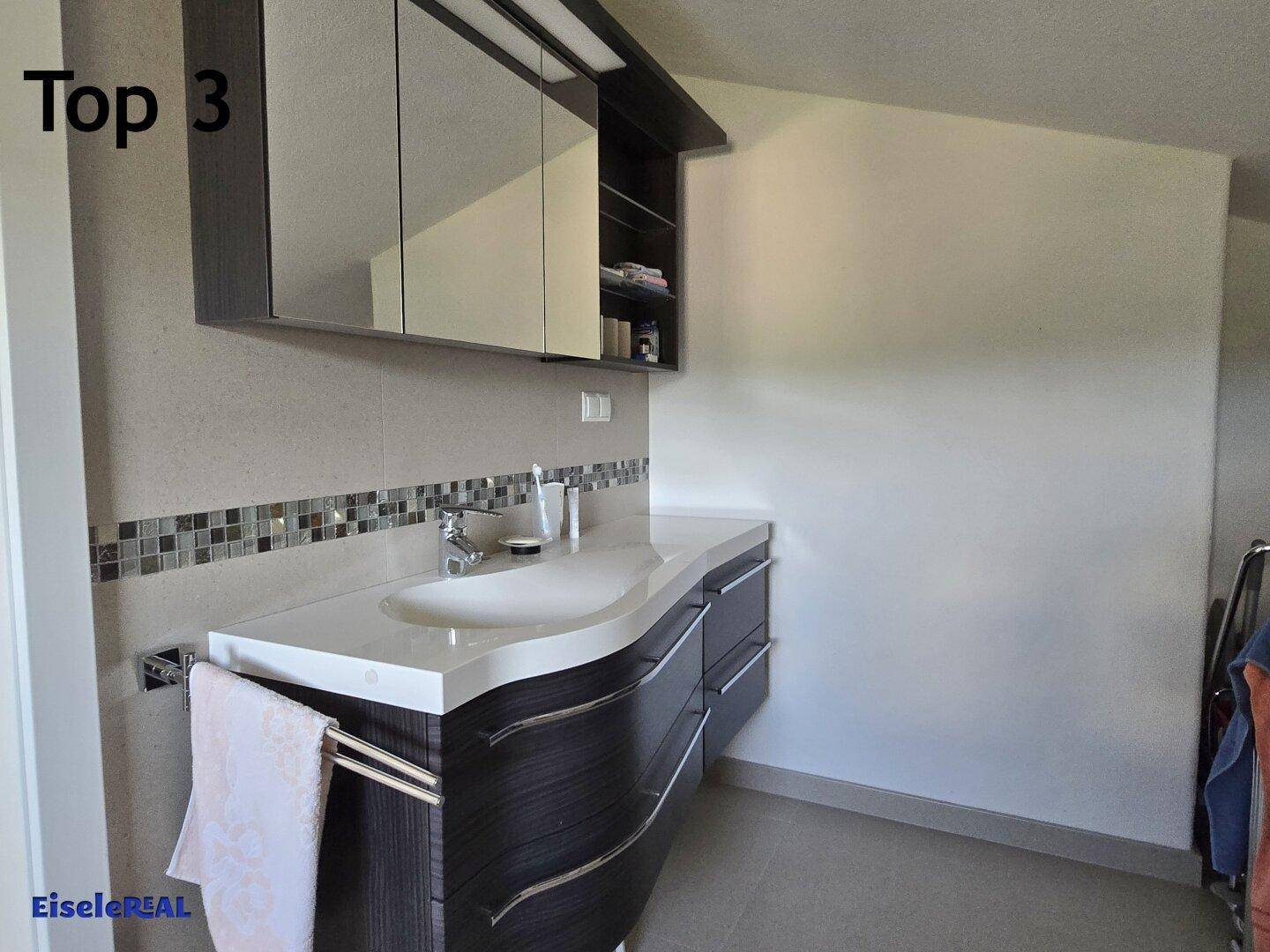 Modernes Badezimmer mit Einzelwaschbecken, Unterschrank und Spiegelschrank, akzentuiert durch Mosaikfliesen.