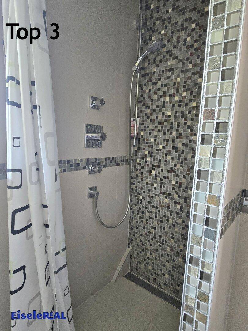 Duschbereich mit modernen Mosaikfliesen und Duschvorhang, der eine praktische Lösung bietet.