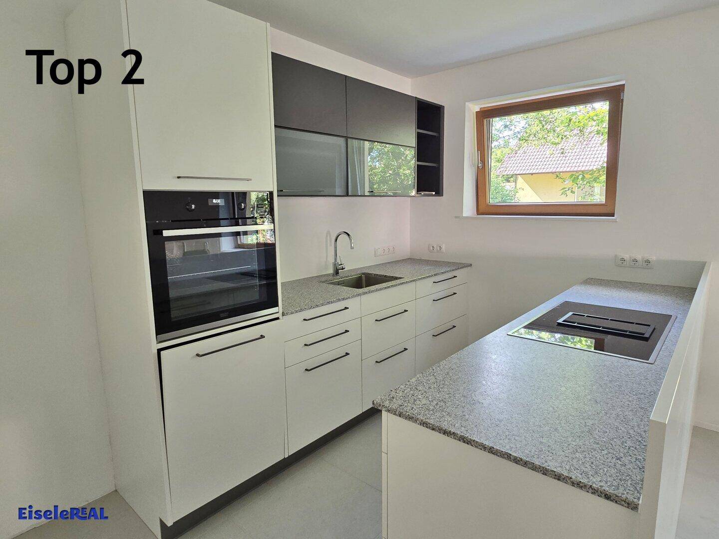 Moderne Einbauküche mit weißen Schränken, Granitarbeitsplatten und integriertem Backofen.