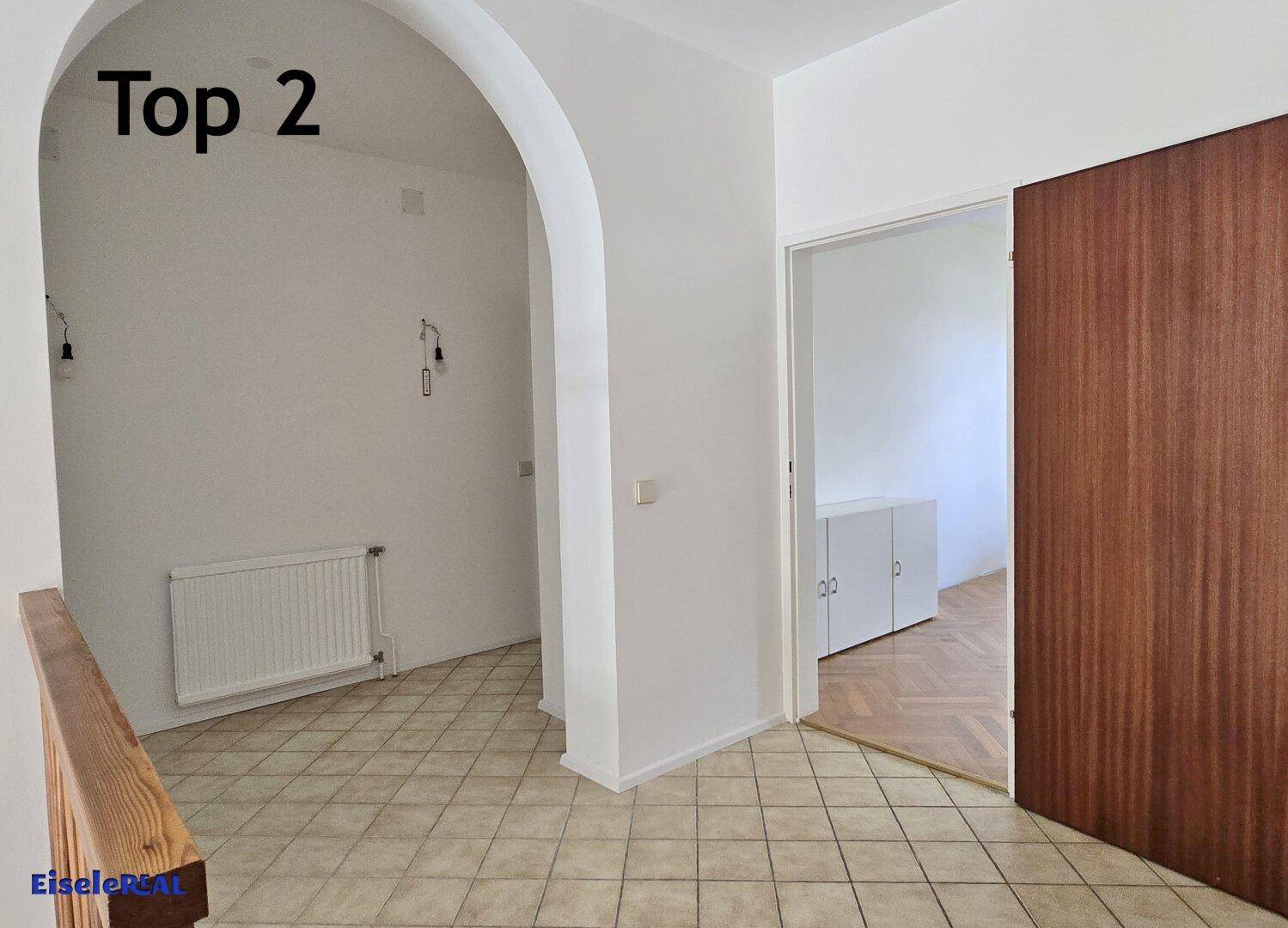 Geräumiger Flur mit Fliesenboden, einem eleganten Bogen und Zugang zu weiteren Räumen.