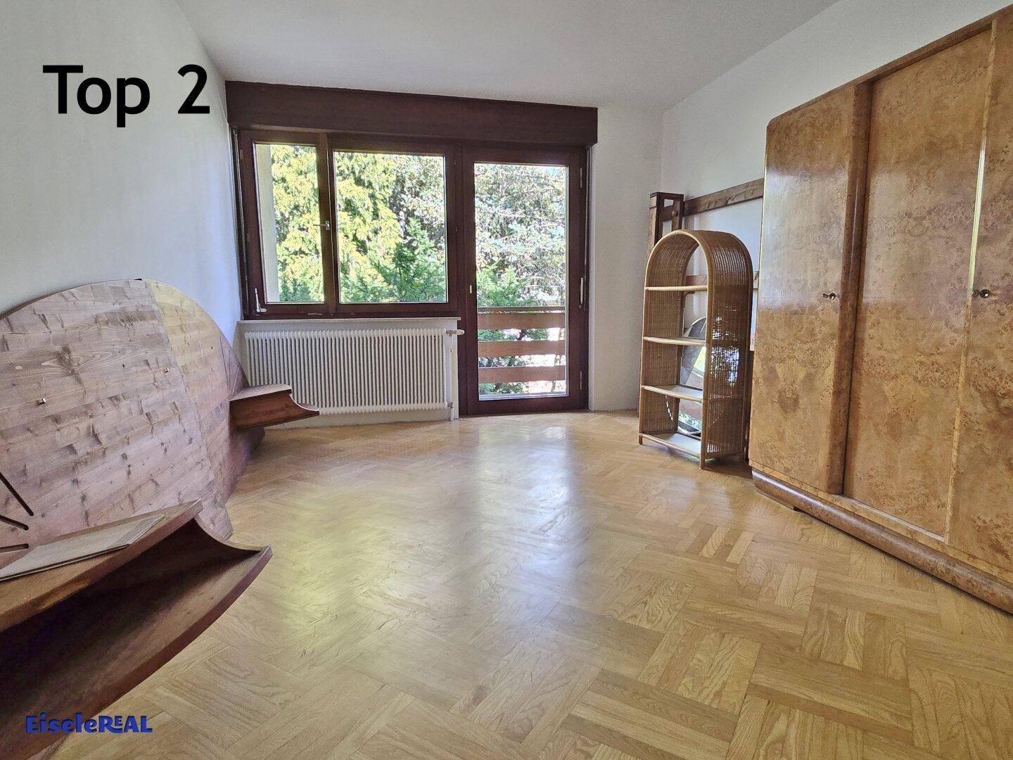 Geräumiges Zimmer mit Parkettboden, großen Fenstern und klassischer Einrichtung.