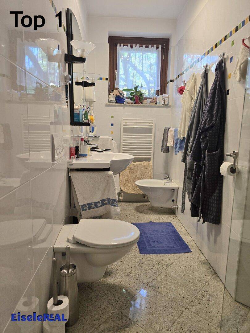 Helles Badezimmer mit WC, Bidet, Waschbecken und beheiztem Handtuchhalter.