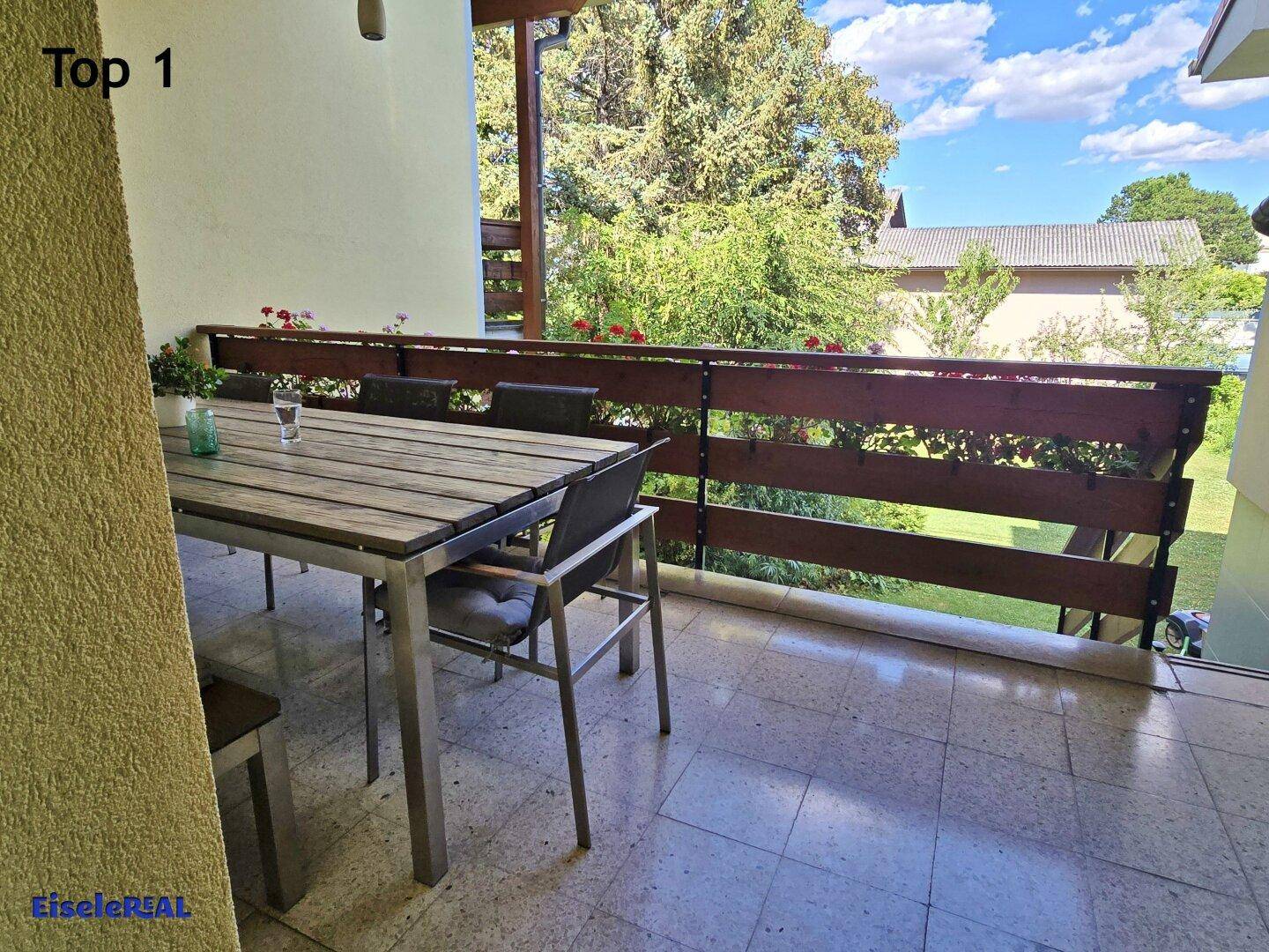 Geräumiger Balkon mit Esstisch, Stühlen und Blick ins Grüne.