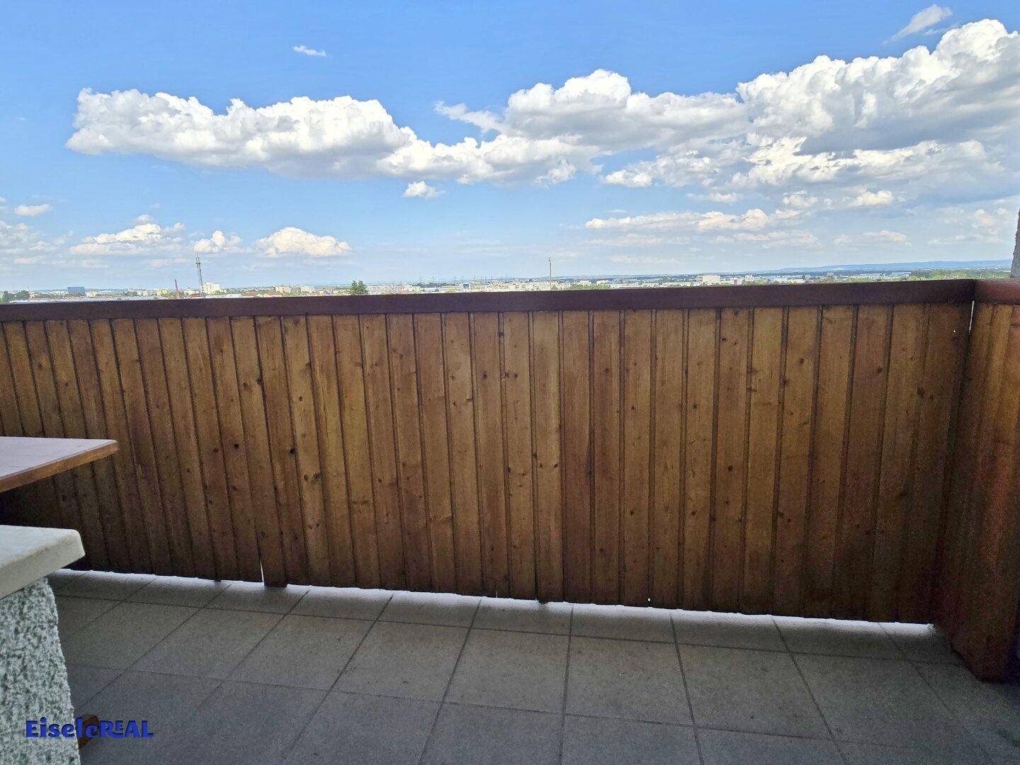 Balkon mit Holzverkleidung und gefliestem Boden bietet einen weiten Blick über die Umgebung.