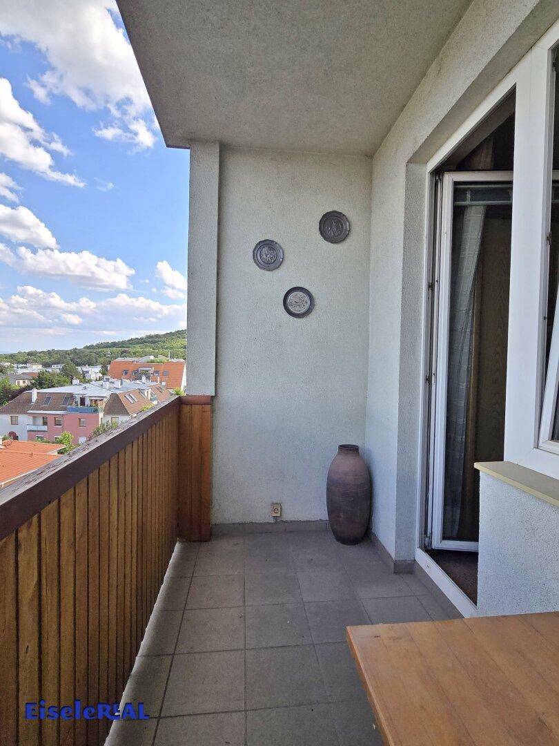 Balkon mit gefliestem Boden und Holzgeländer bietet einen weiten Blick über die Dächer.