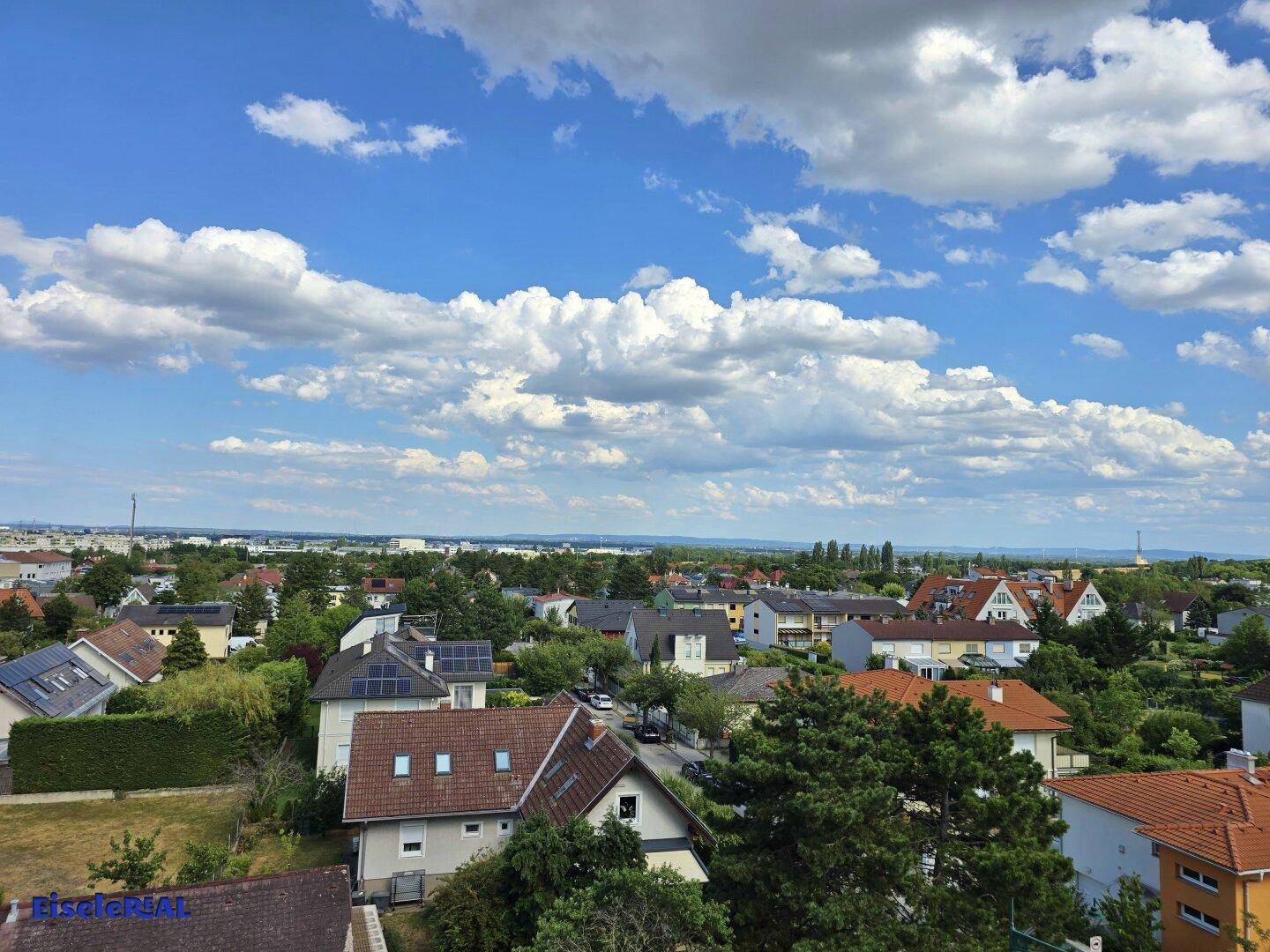 Weiter Ausblick über die umliegende Wohngegend mit Bäumen und blauen Himmel.