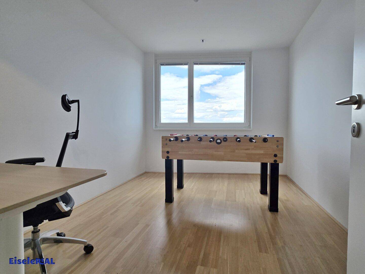 Heller Raum mit einem Kickertisch und einem Schreibtisch, ideal für Freizeit oder Büro.