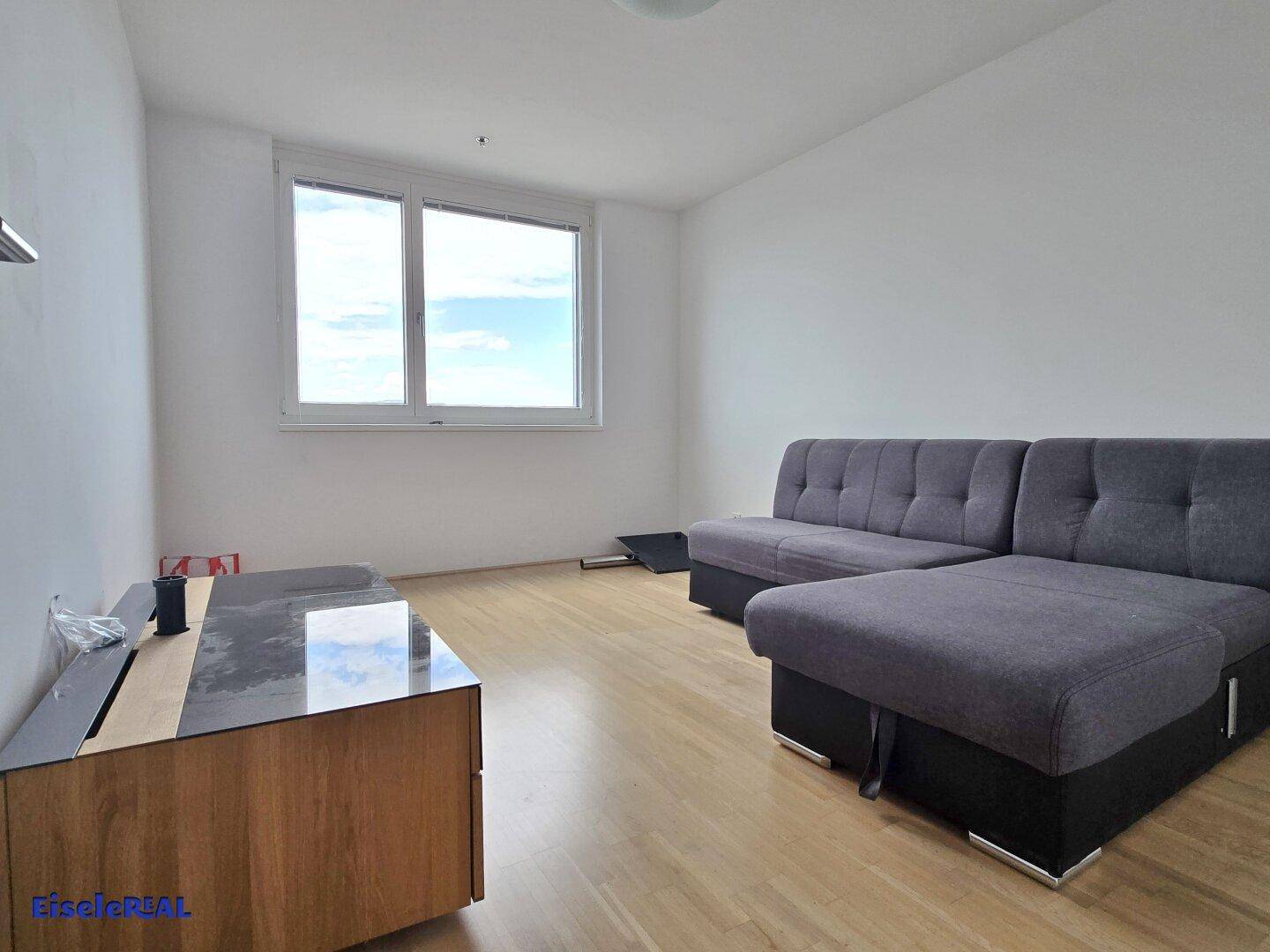 Gemütliches Wohnzimmer mit grauem Sofa, modernem TV-Möbel und hellem Holzboden.