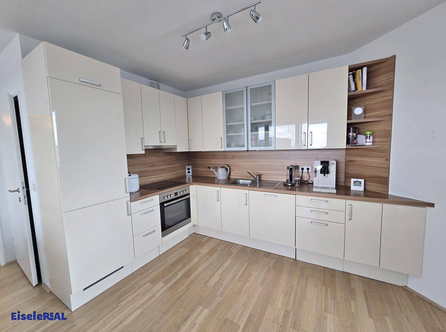 Moderne Einbauküche mit hellen Schränken, Holz-Arbeitsplatten und integrierten Geräten.
