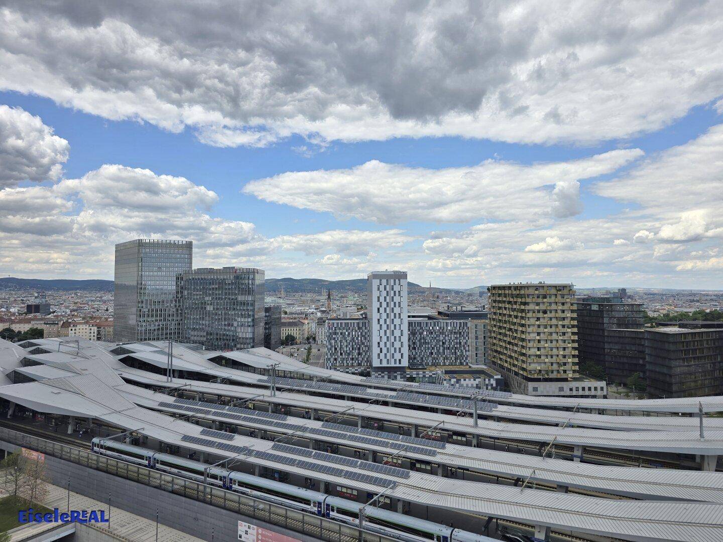 Weitwinkelaufnahme der Stadt mit einem modernen Bahnhof und markanten Gebäuden im Hintergrund.