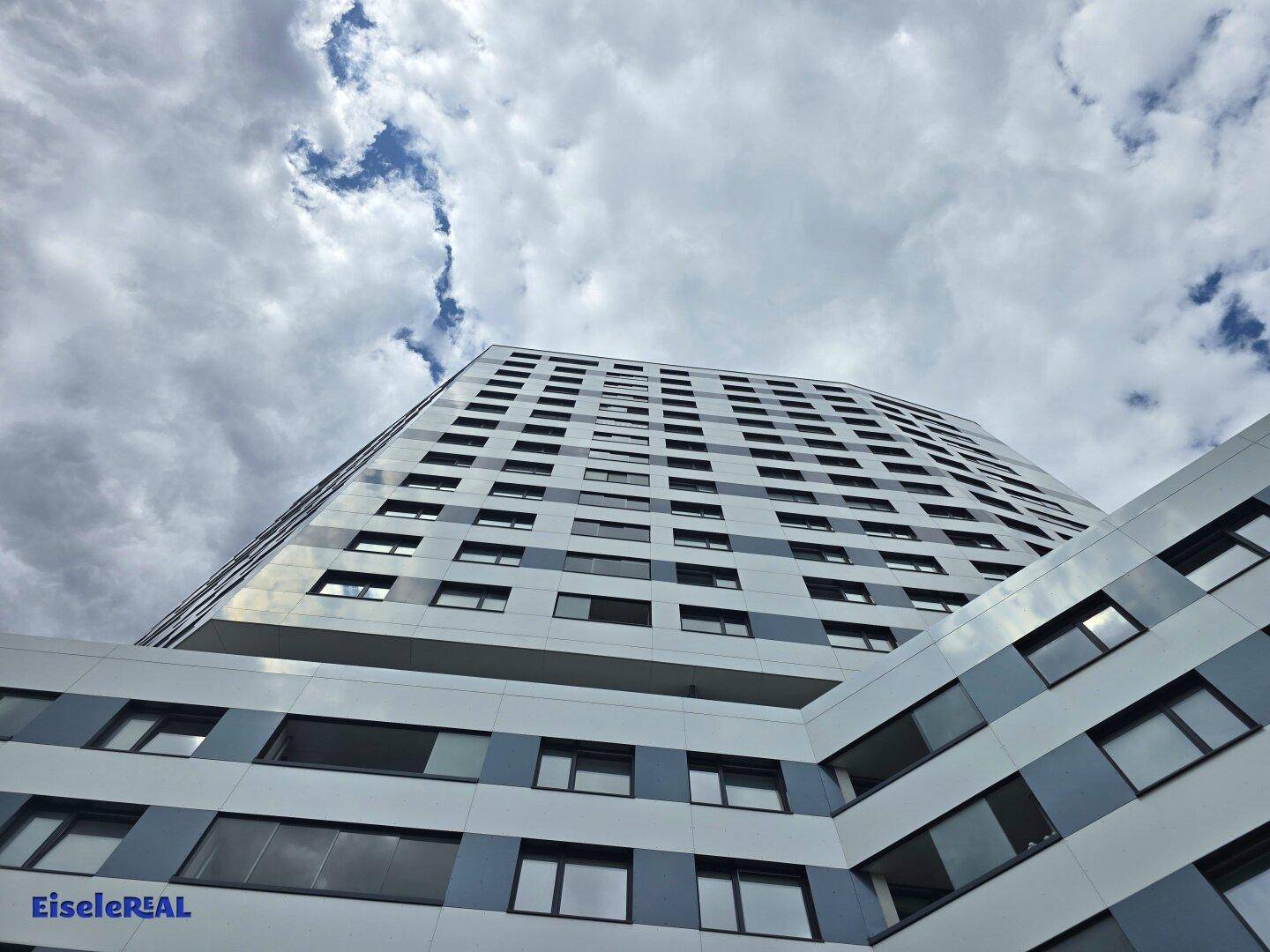 Ansicht eines modernen Hochhauses mit markanter Architektur unter einem bewölkten Himmel.