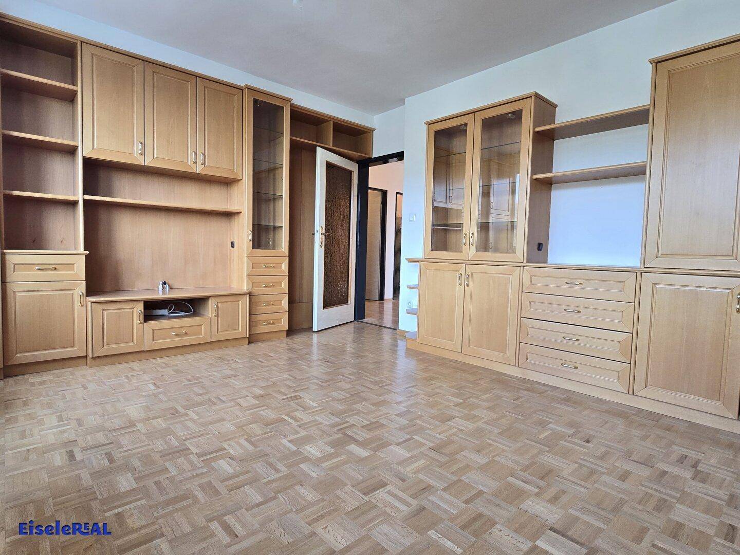 Wohnzimmer mit umfangreichen Holzschränken und Zugang zu weiteren Räumen.