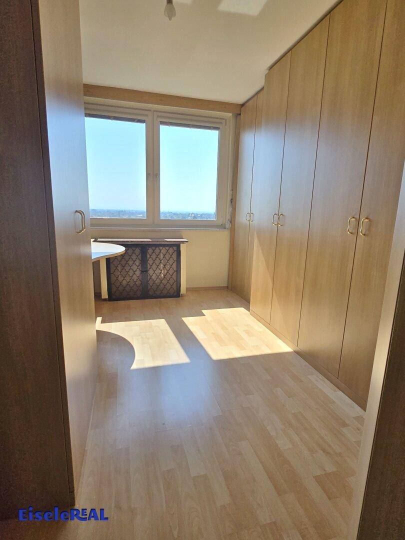 Schlafzimmer mit Holzboden und Einbauschränken entlang der Wand.