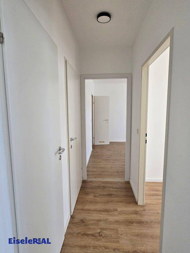 Langer Flur mit Laminatboden und mehreren Türen, der zu verschiedenen Räumen führt.