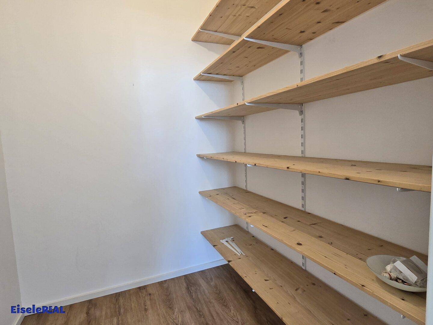 Praktischer Abstellraum mit mehreren Holzregalen, ideal für zusätzlichen Stauraum.