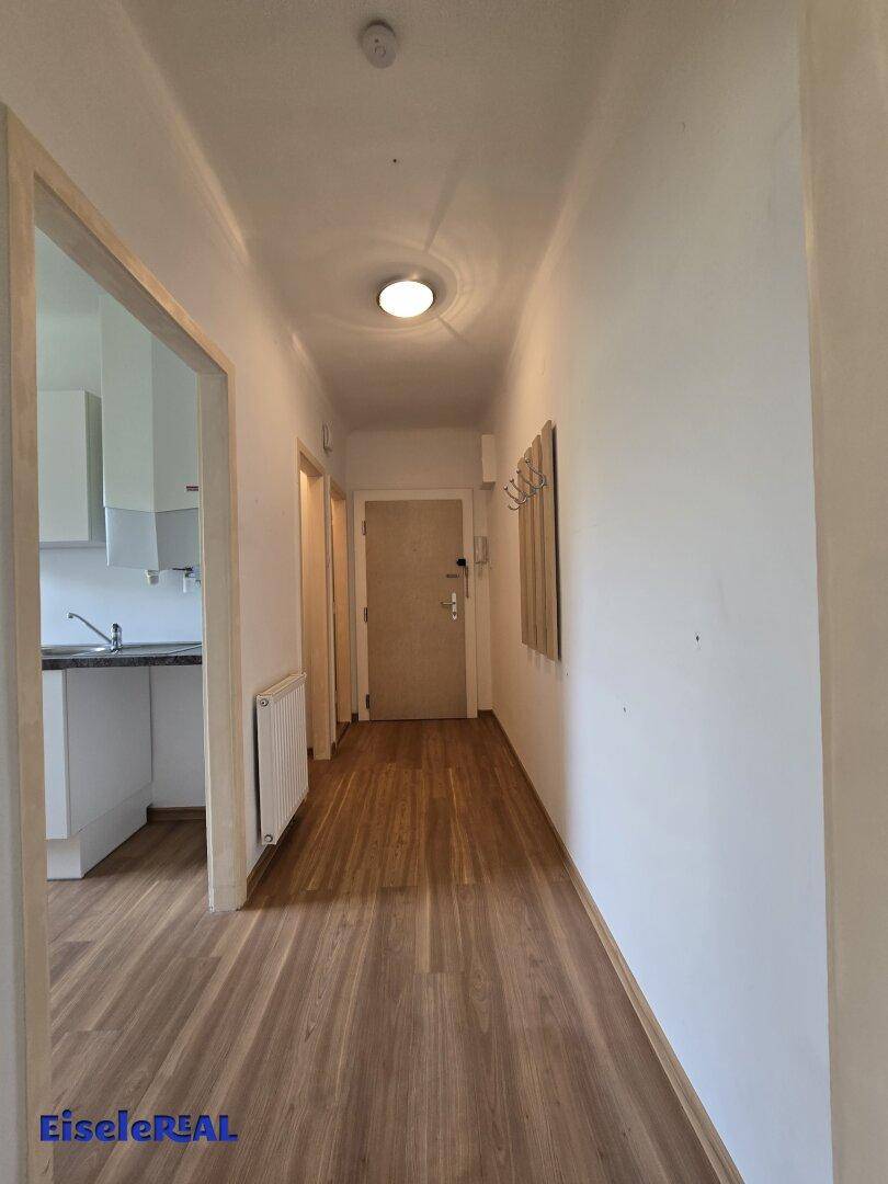 Heller Flur mit Laminatboden, Garderobe und Zugang zu verschiedenen Räumen.