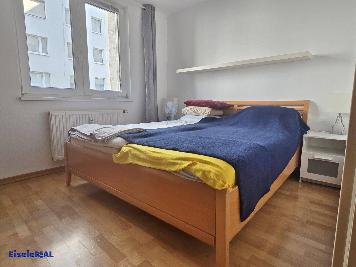 Schlafzimmer mit Doppelbett, Nachttisch und großem Fenster für viel Tageslicht.
