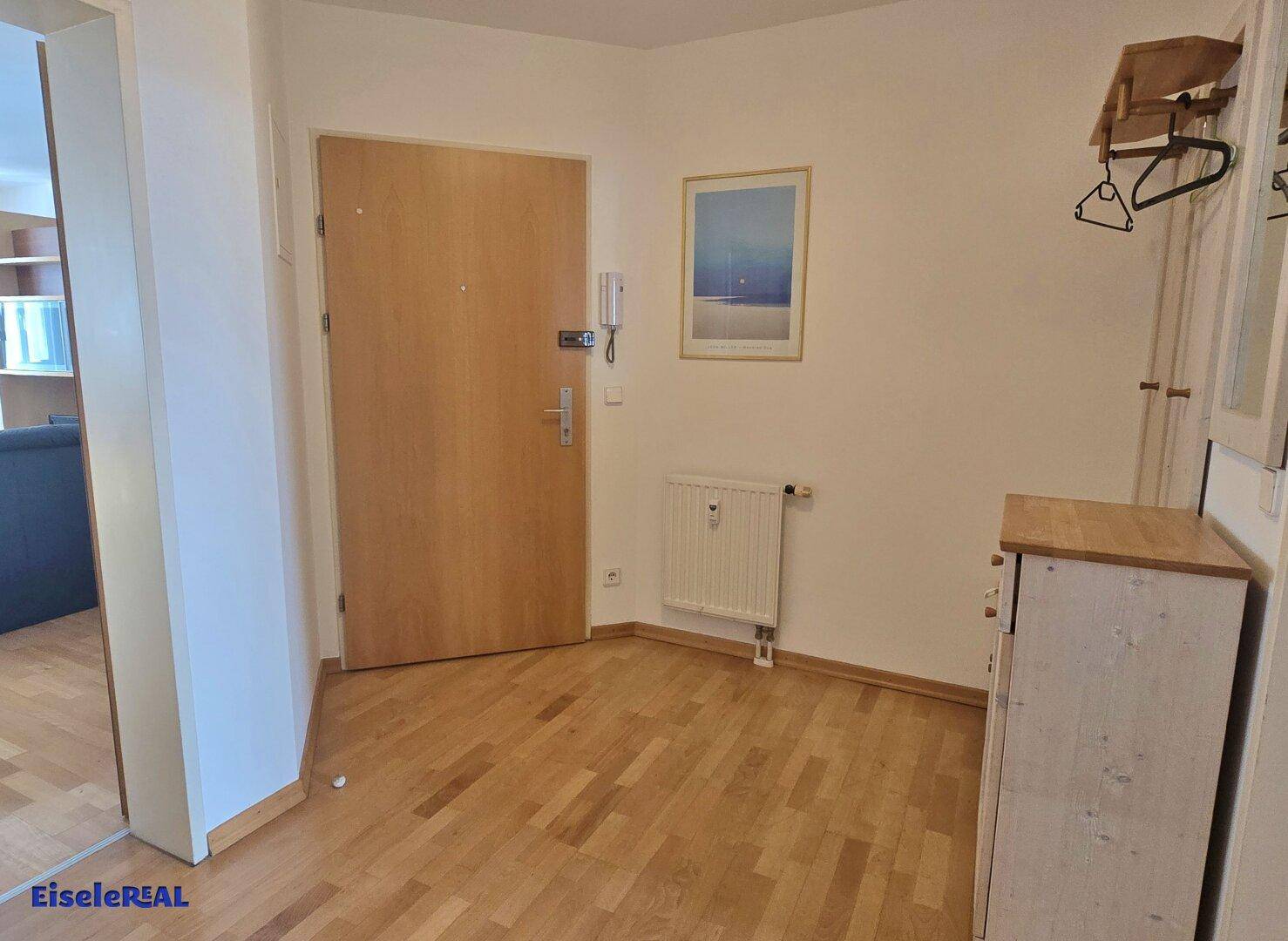 Heller Eingangsbereich mit Holzboden, Garderobe und Gegensprechanlage.