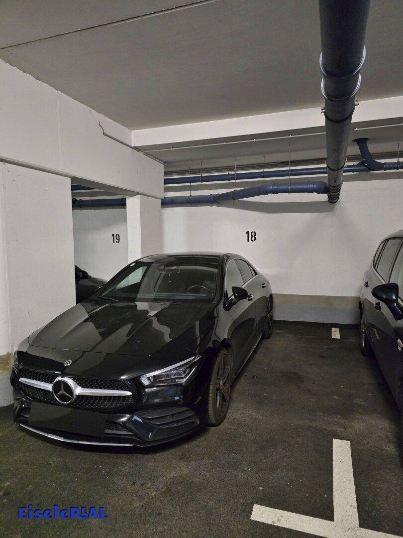 Tiefgarage mit markierten Stellplätzen, sichtbaren Leitungen und solider Betonkonstruktion.