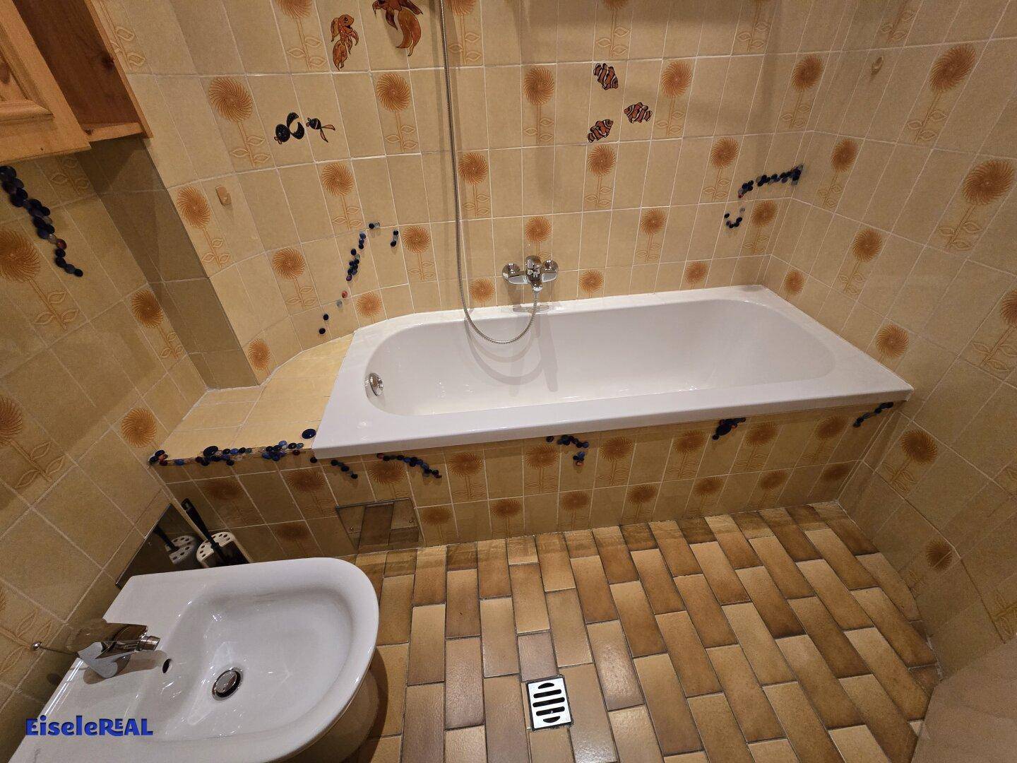 Badezimmer mit Badewanne, Bidet und gefliesten Wänden und Böden.