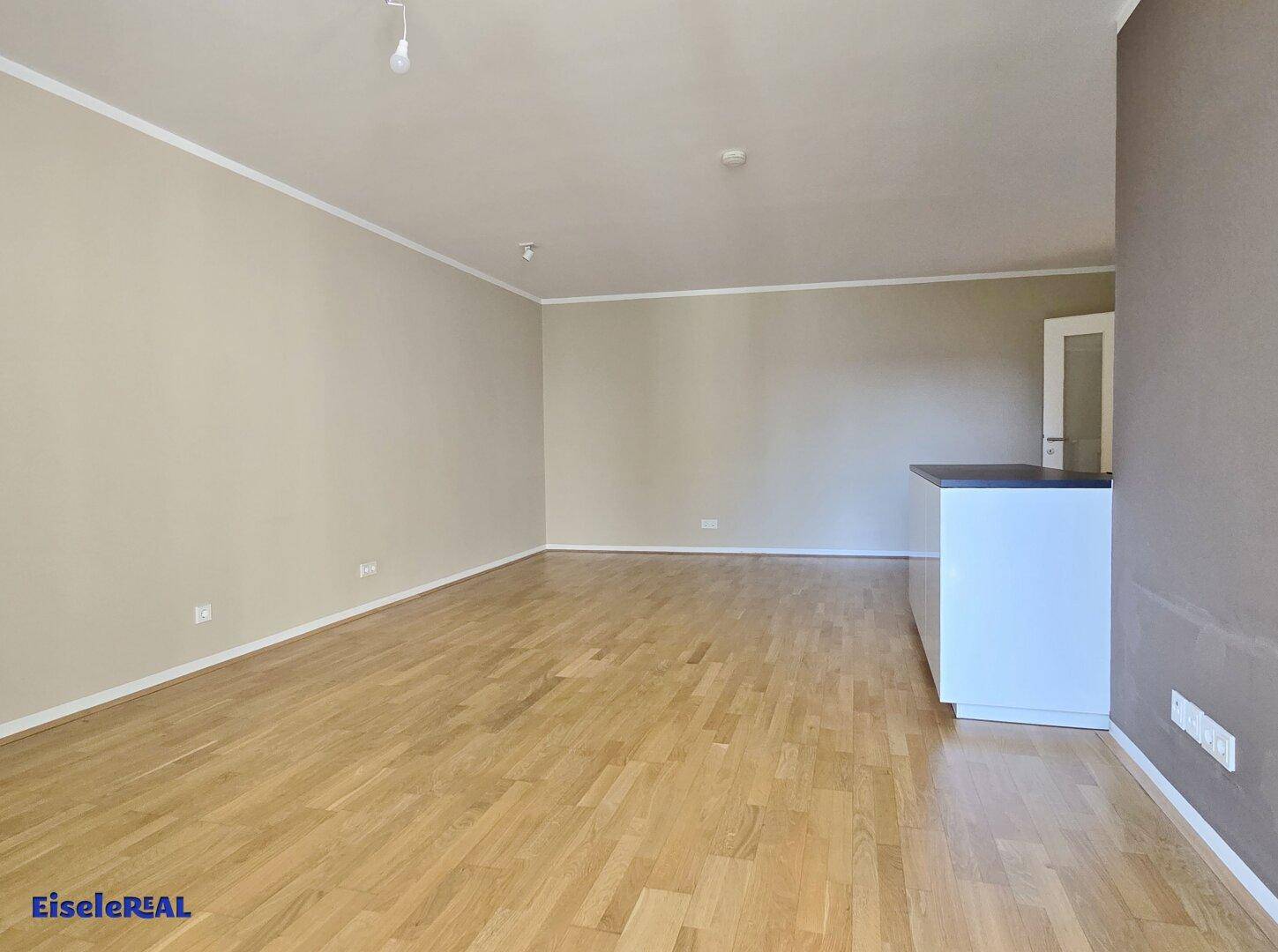Geräumiges Wohnzimmer mit hellem Holzboden und neutralen Wänden, bereit zur Einrichtung.
