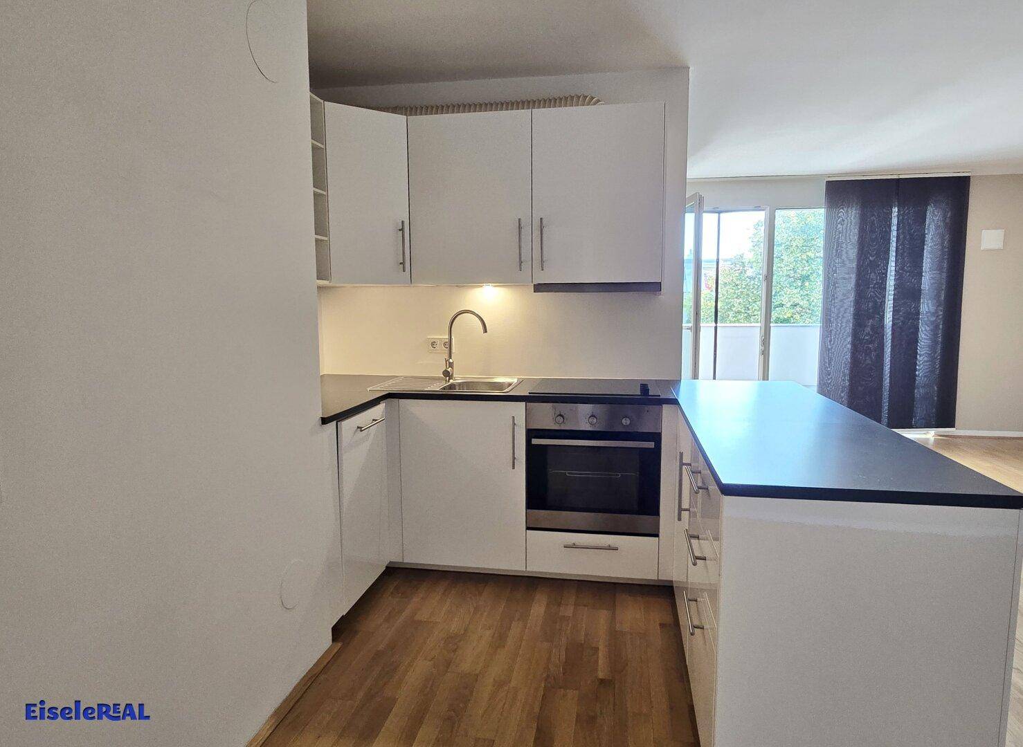 Funktionale Küche mit Einbauherd, Spüle und ausreichend Arbeitsfläche in modernem Design.