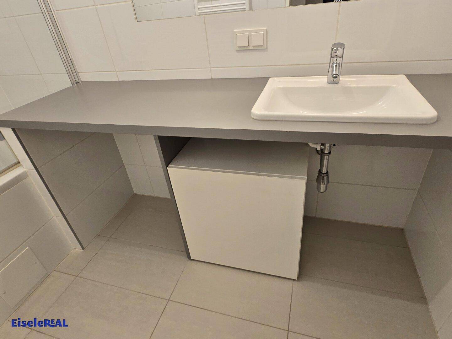 Badezimmer mit modernem Waschtisch, Einzelwaschbecken und grauer Ablagefläche.