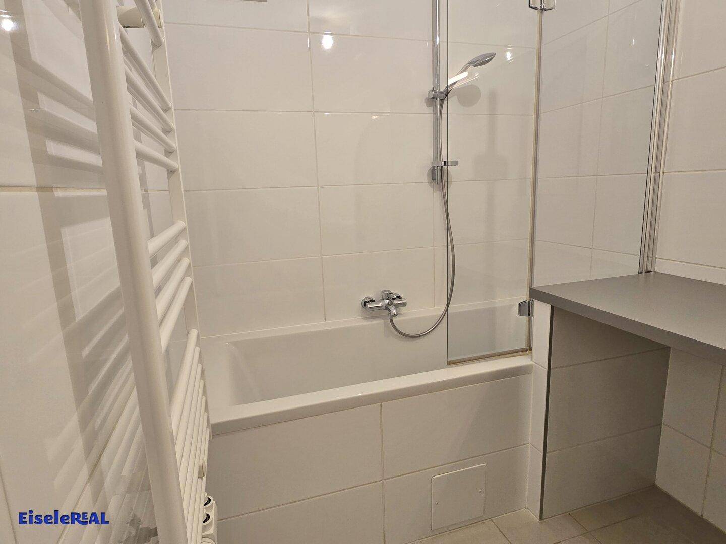 Badezimmer mit Badewanne, Duschfunktion und praktischem Handtuchheizkörper.