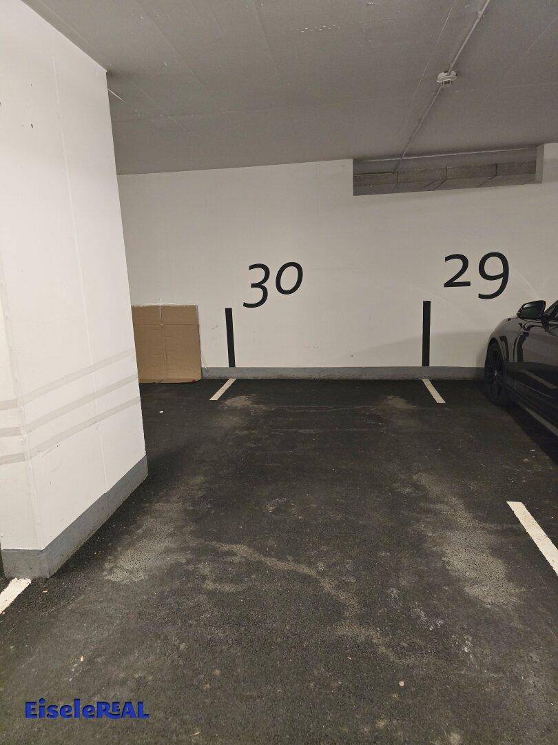 Tiefgaragenstellplatz in einer gut beleuchteten und sauberen Parkgarage mit nummerierten Parkplätzen.