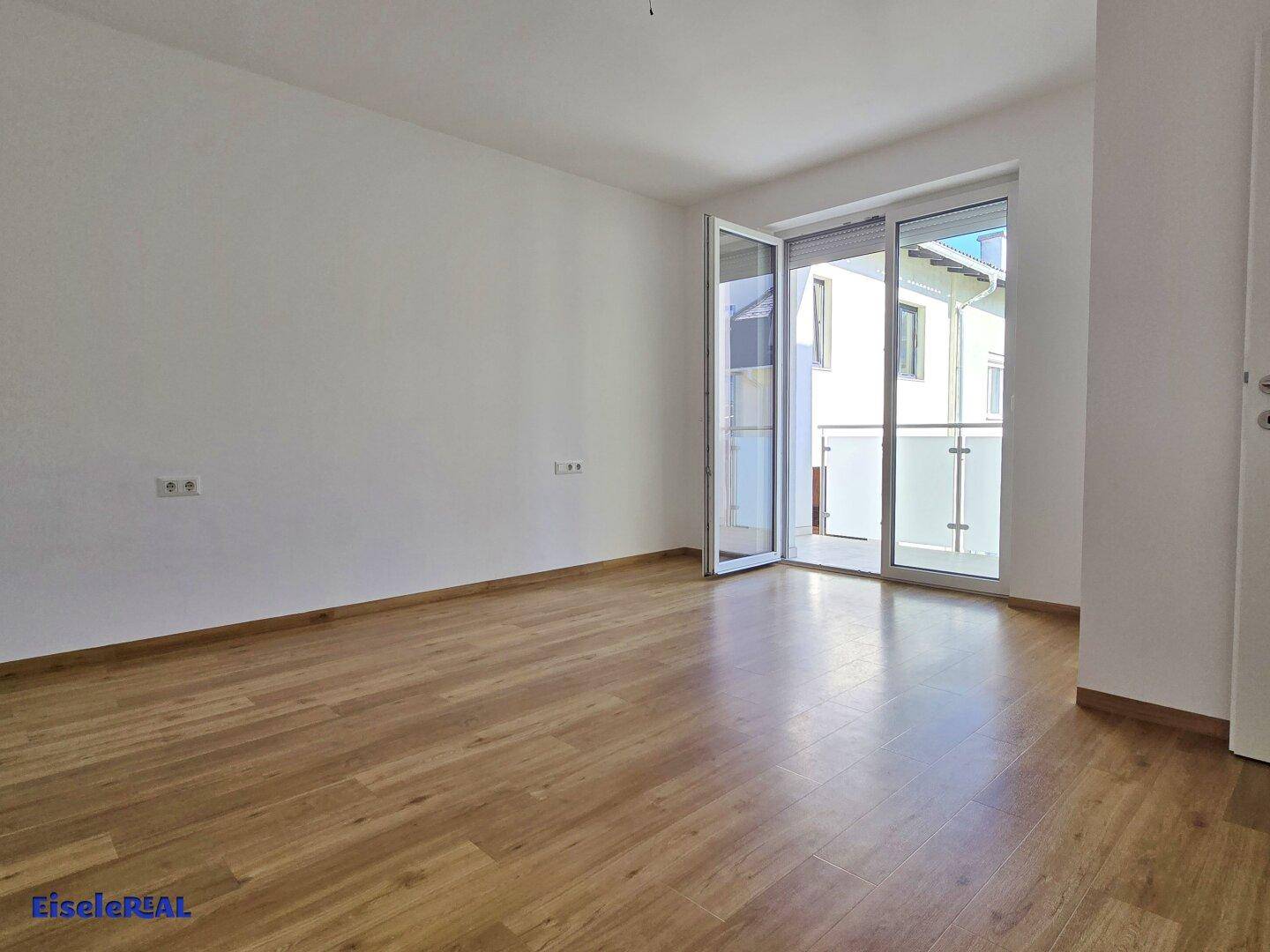 Helles Zimmer mit Laminatboden und Zugang zu einem Balkon, ideal als Schlaf- oder Wohnraum nutzbar.