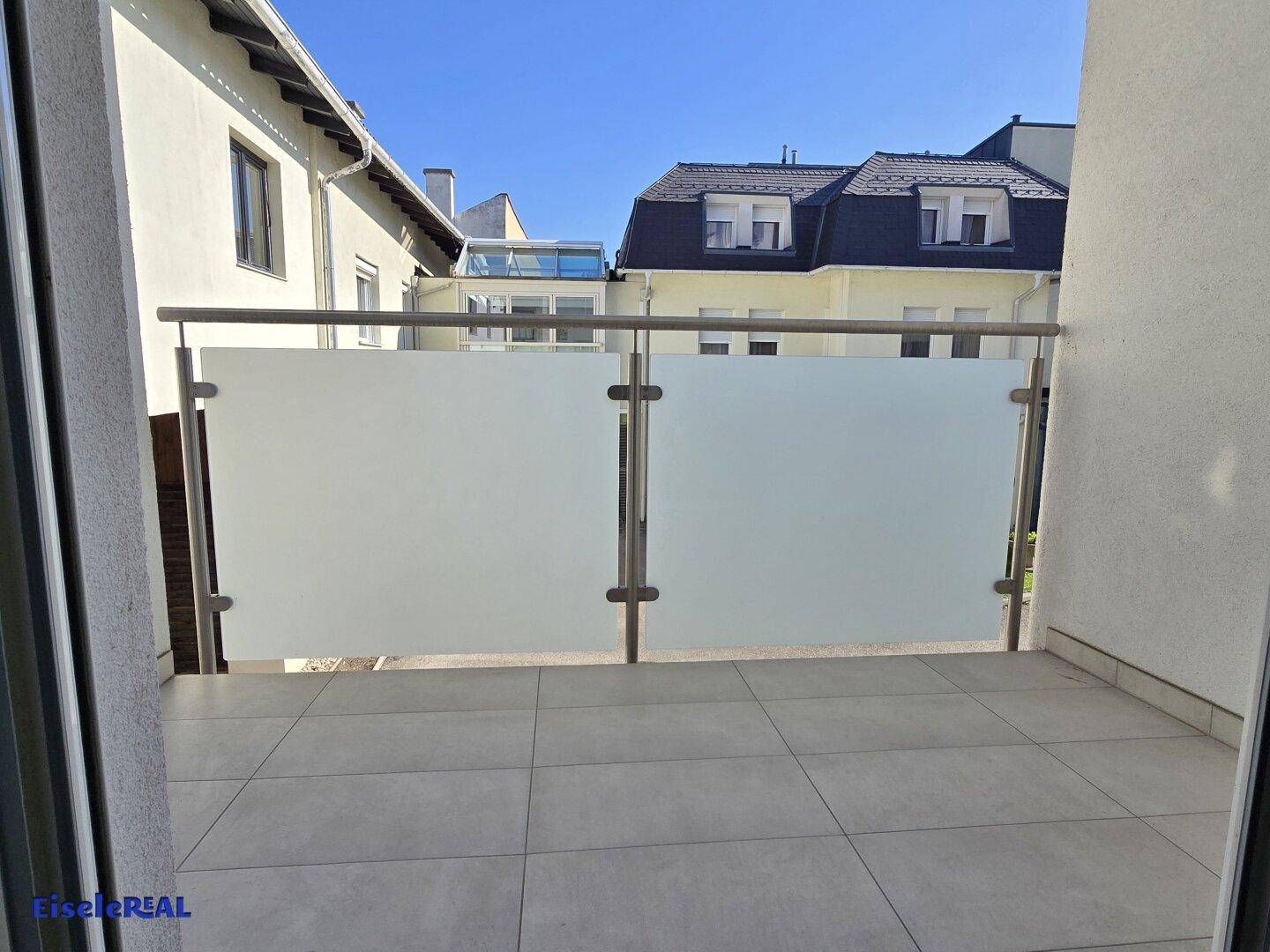 Balkon mit Fliesenboden und blickdichtem Glasgeländer, bietet Privatsphäre und einen schönen Ausblick.