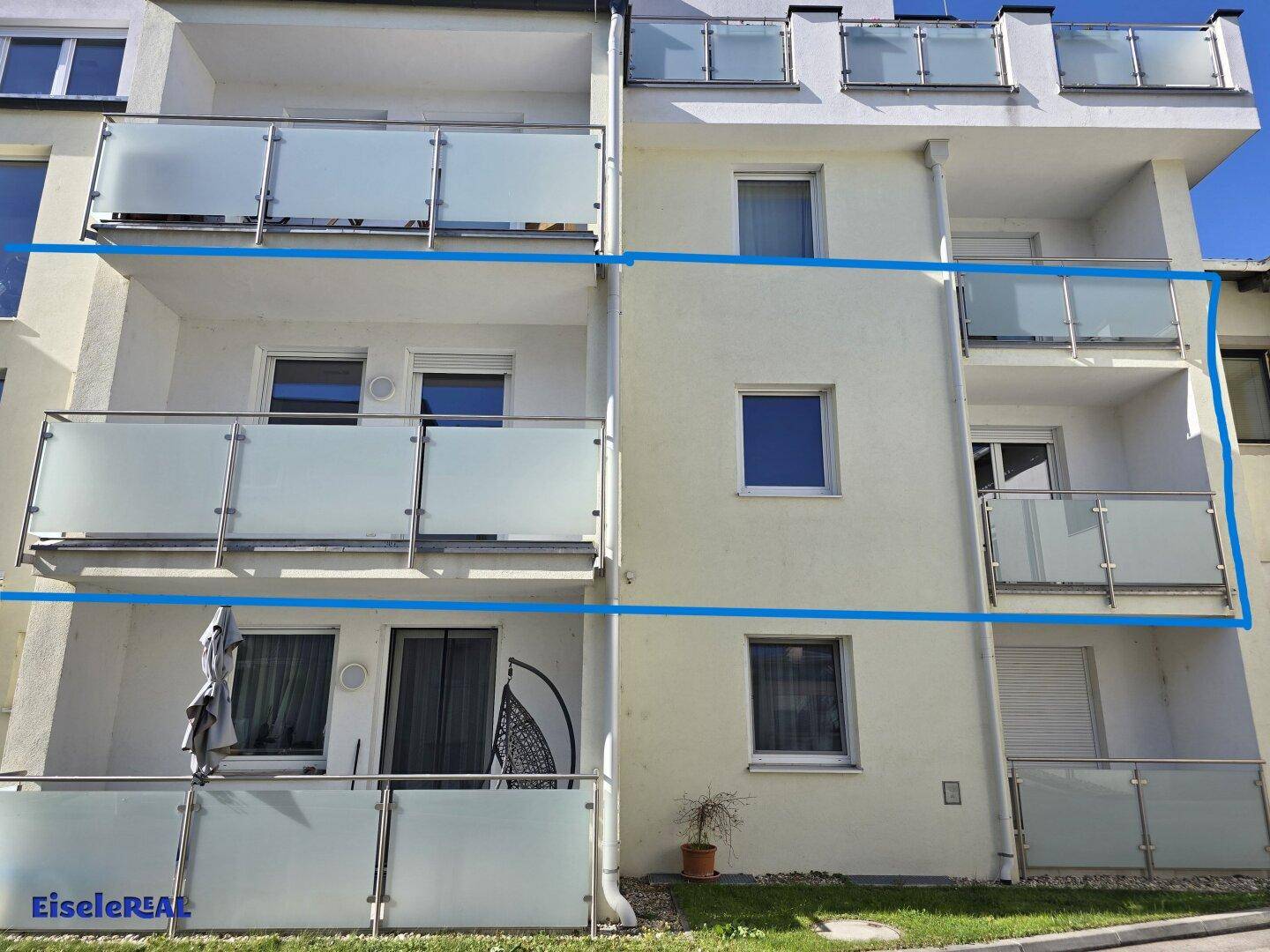 Detailansicht der modernen Fassade mit mehreren Balkonen und Glasgeländern, die das Gebäude schmücken.