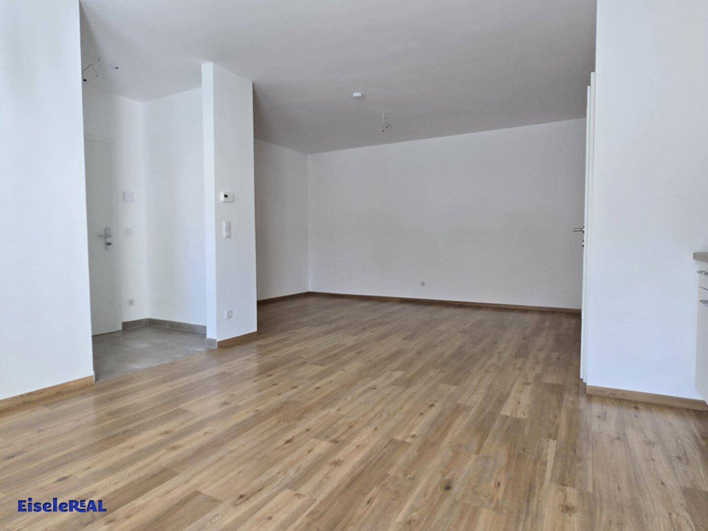 Geräumiger, heller Wohnbereich mit neuem Laminatboden und weißen Wänden, bereit zur individuellen Gestaltung.