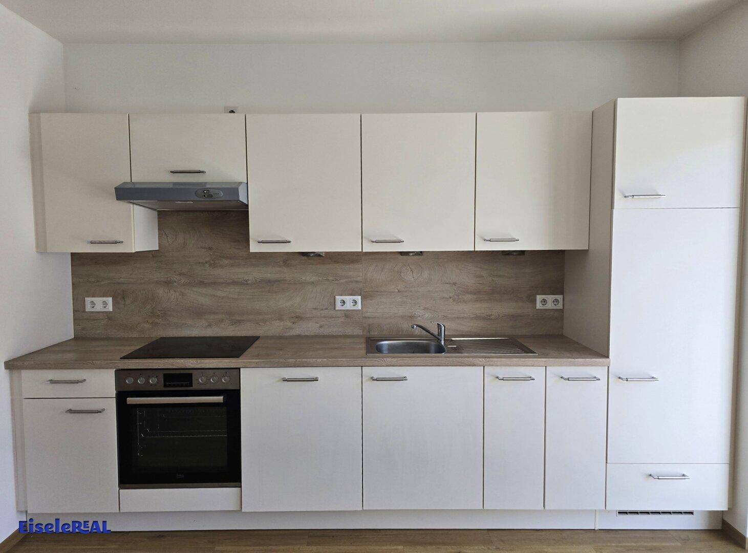 Moderne Einbauküche mit weißen Schränken, Holzoptik-Arbeitsplatte und integrierten Geräten für den täglichen Gebrauch.