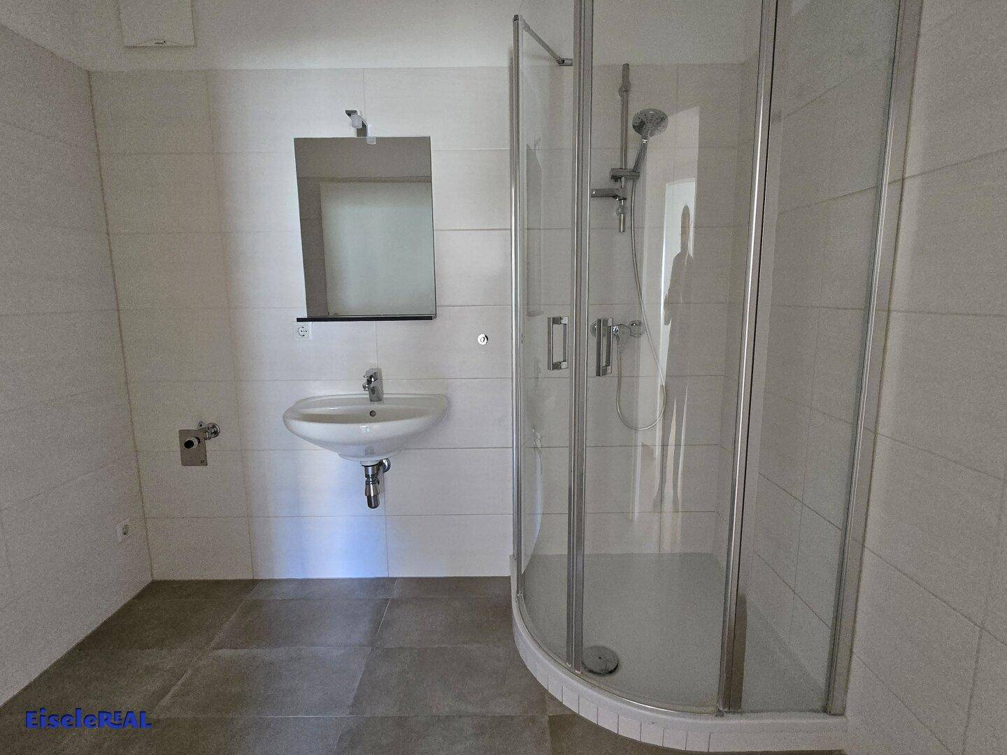 Helles Badezimmer mit Duschkabine, Waschbecken und Spiegel, ausgestattet mit modernen Fliesen.
