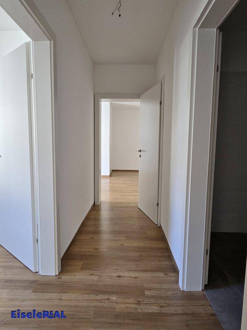 Heller Flur mit Laminatboden und weißen Türen, der die Räume der Wohnung verbindet.