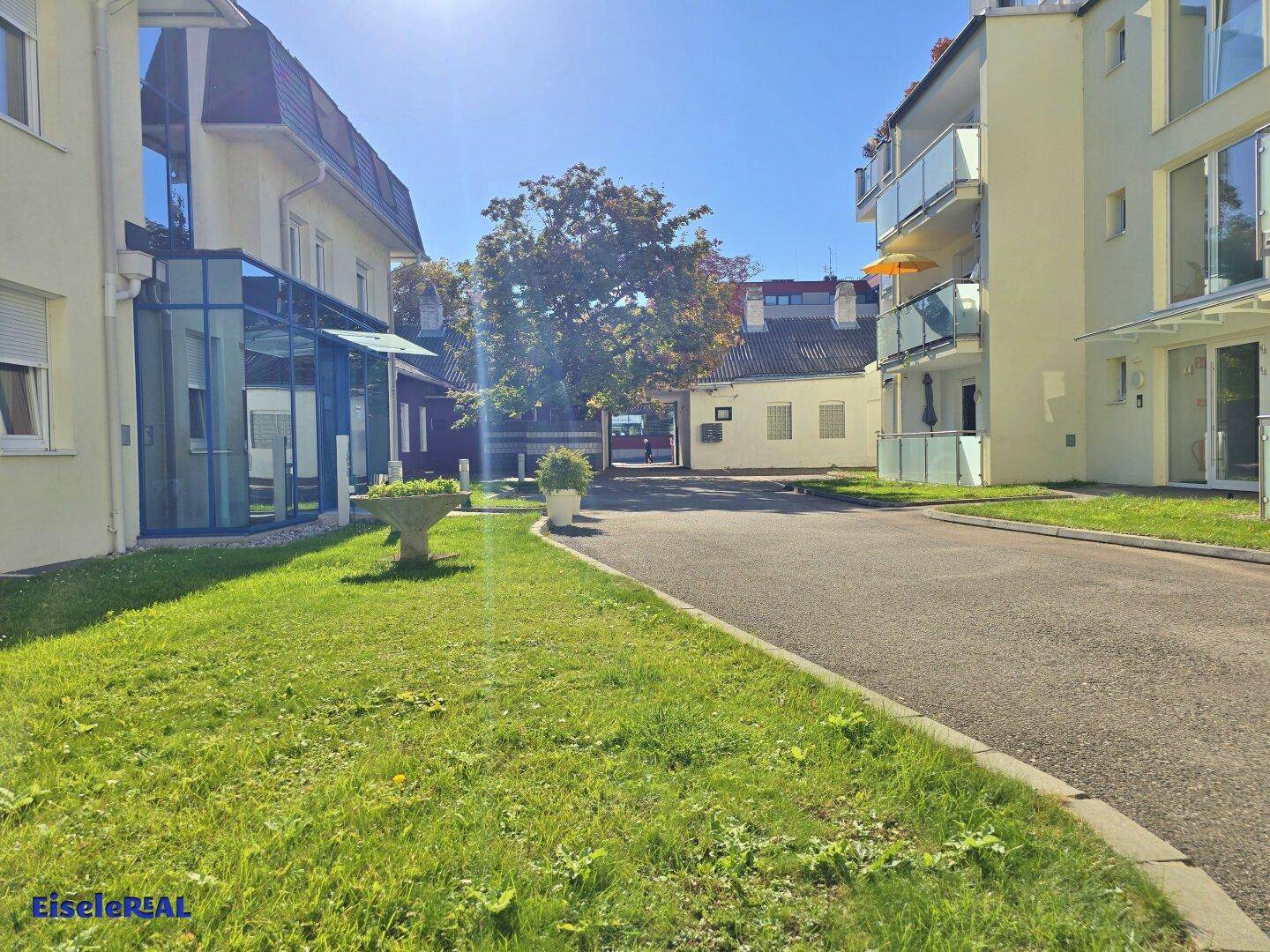 Außenbereich des Anwesens mit gepflegter Rasenfläche und Zufahrt, umgeben von weiteren Gebäuden.