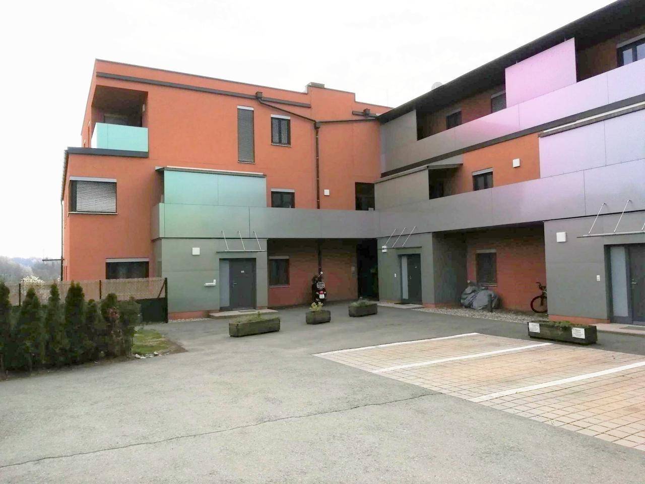 Ansicht der modernen Wohnanlage mit orangefarbener Fassade und Parkmöglichkeiten.