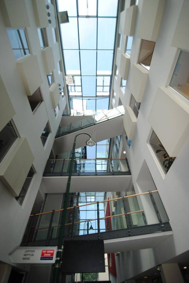 Atrium mit Glasdach, mehreren Etagen und einem modernen Design.